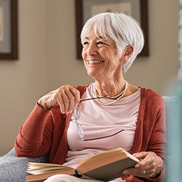 Senior woman smiling while reading at home