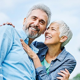 Senior couple smiling while hugging outside