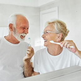 Senior couple smiling while brushing their teeth