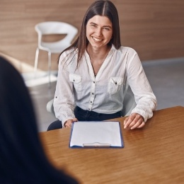 Dental team member with clipboard smiling at dental patient