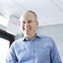 Man in light blue collared shirt talking to dental team member