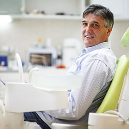Older man sitting in dental chair and smiling