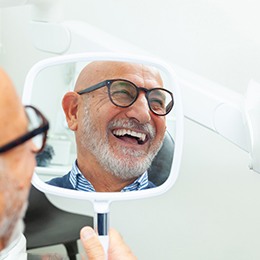 Senior man checking smile in mirror