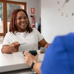 Woman handing a payment card to a dental team member at front desk