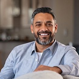 Man in blue shirt smiling while sitting on couch