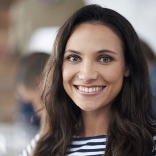 Brunette woman smiling after gum disease treatment in Nepean