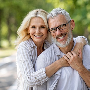 Senior woman hugging senior man from behind