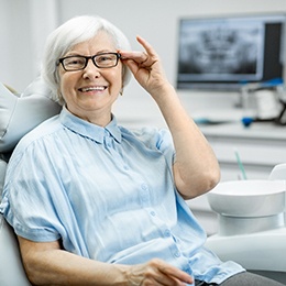 Senior woman with glasses smiling in dental chair