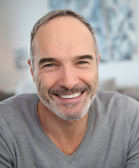 Man in gray cardigan smiling