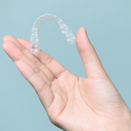 Closeup of patient holding Invisalign aligner