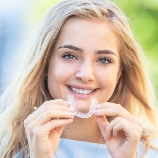 Young blonde woman holding Invisalign in Nepean
