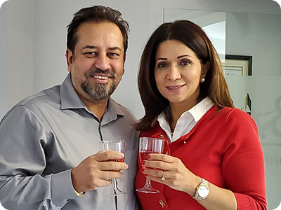 Doctor Bal smiling and holding wine glasses with a woman