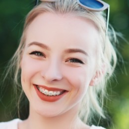 Young blonde woman with traditional braces smiling outdoors