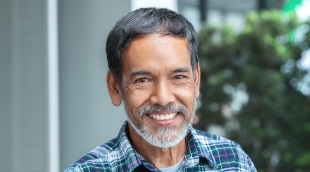 Man in plaid shirt grinning outdoors