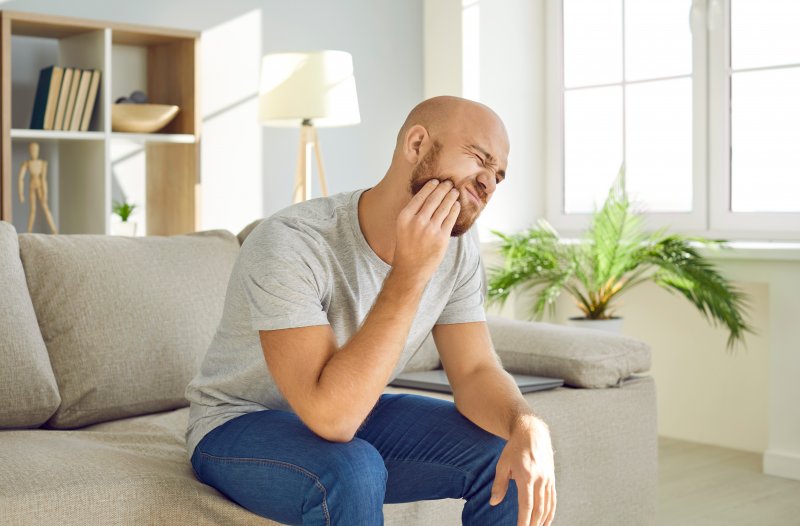 Man holding his jaw due to dry socket