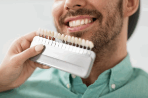 Dentist comparing a row of dental veneers to patient’s natural teeth