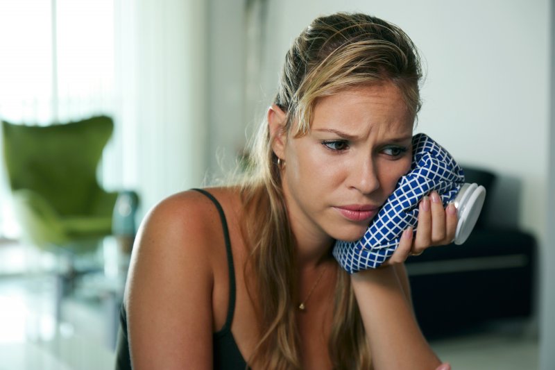 A woman using a cold compress to treat her severe toothache